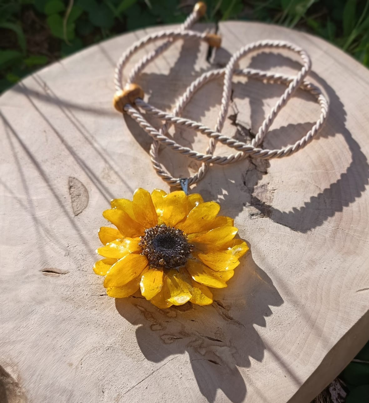 Colar de girassol amarelo com cordão trançado sobre madeira