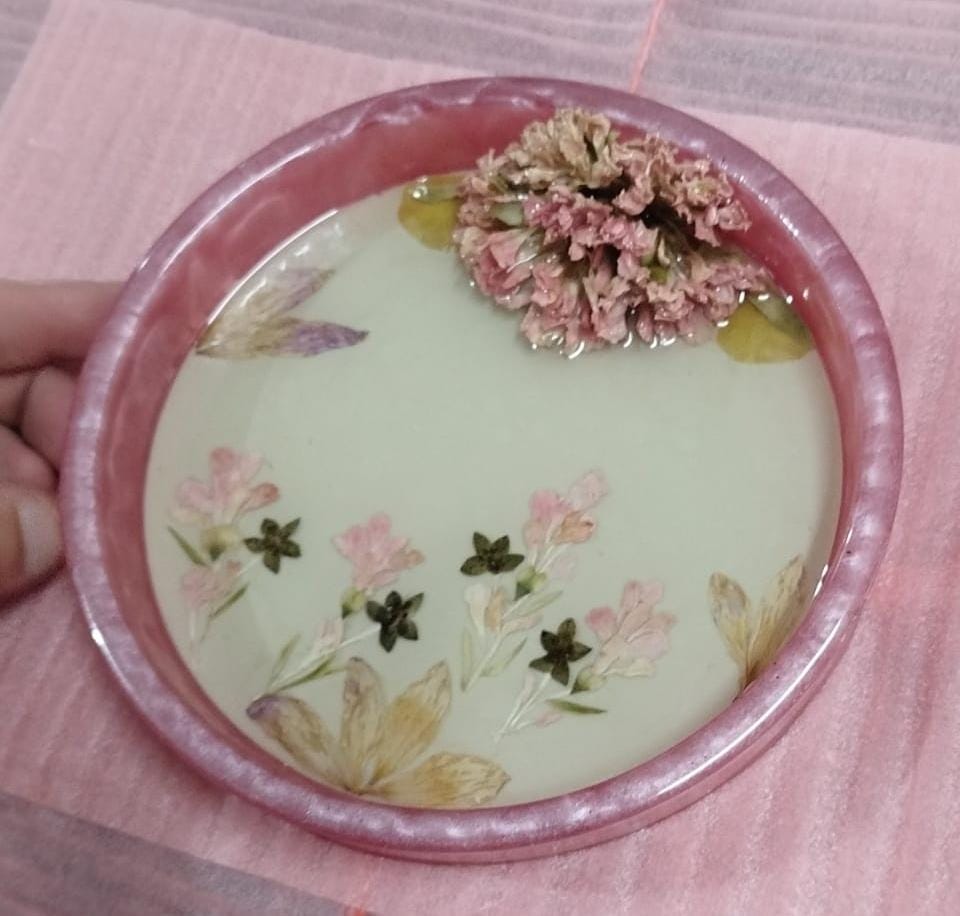 Peça circular de resina com flores e borda rosa